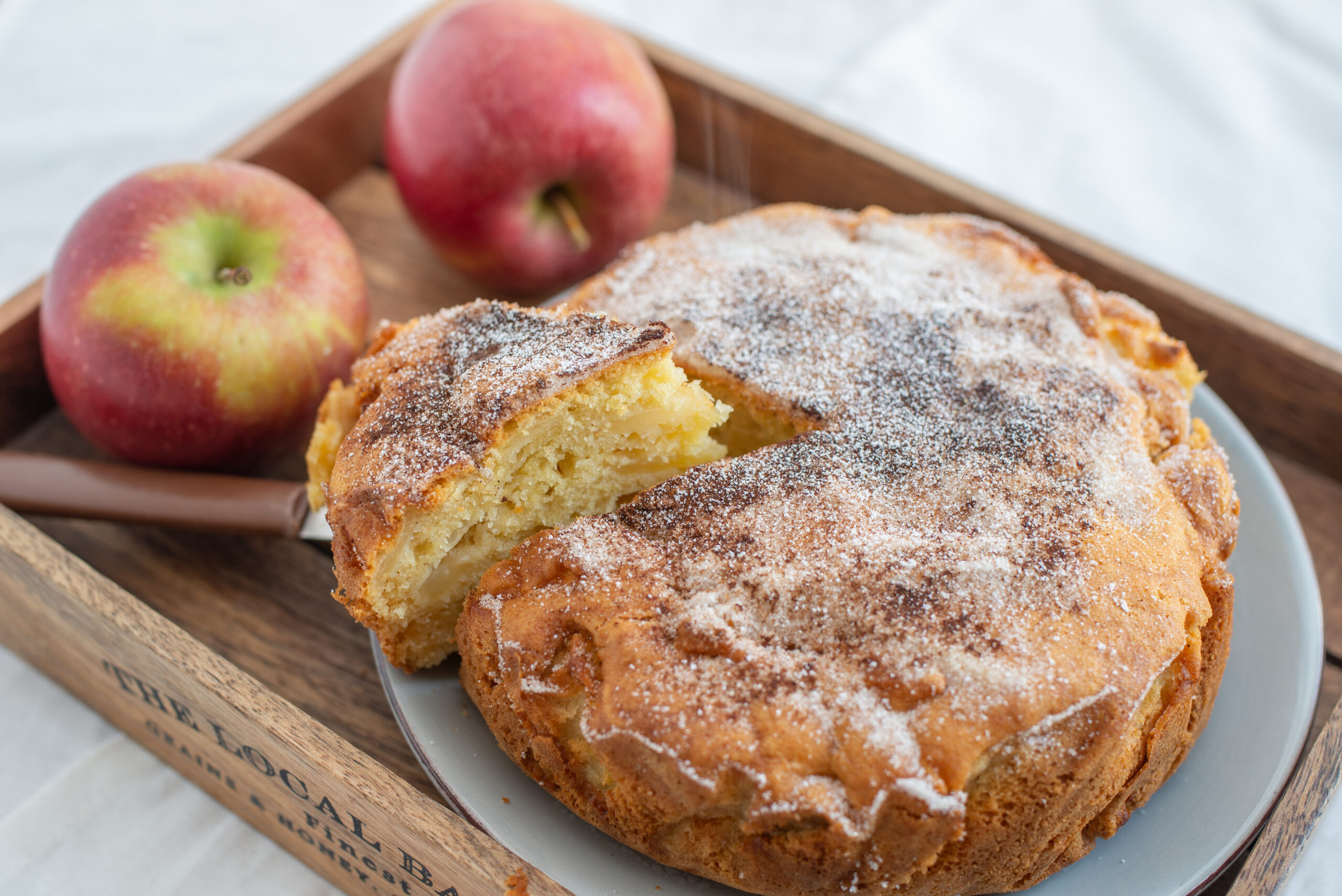 A freshly baked Cinnamon Apple Cake on a cooling rack, garnished with cinnamon sticks and apple slices.