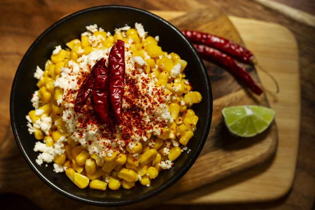 Creative serving suggestion for Chipotle Corn Salsa with tortilla chips and fresh lime wedges.