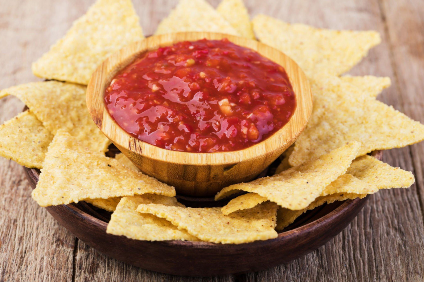Serving fresh salsa with a clean spoon to avoid cross-contamination.